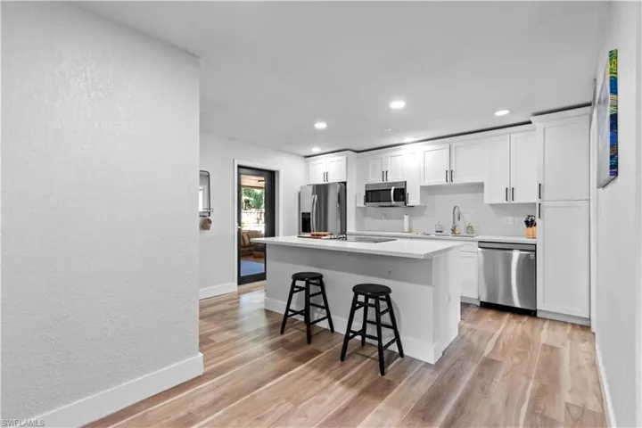 Kitchen with a kitchen bar, white cabinetry, Quartz counters, stainless steel appliances, recessed lighting, and an island