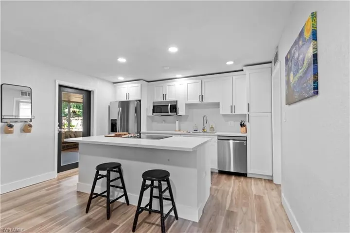 Kitchen with soft-close cabinets and drawers, a center island with flat top stop, recessed lighting, a breakfast bar, and door leading to the lanai