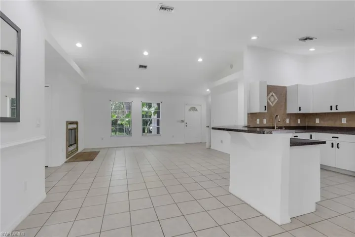 Spacious room featuring neutral-toned tile flooring, recessed lighting, a built-in fireplace, and expansive windows