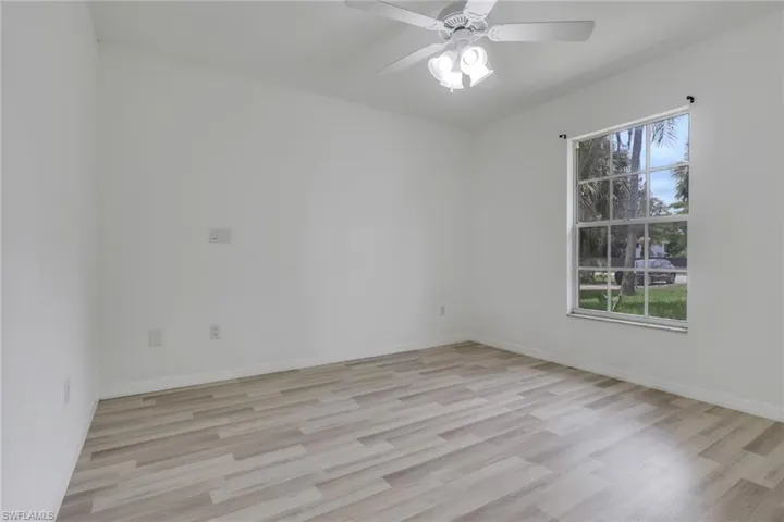 Room featuring wood-finish flooring, white walls, and a multi-pane window with a white frame