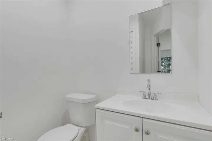 Bathroom featuring a single vanity with a white countertop and integrated sink, chrome-finish faucet, and a rectangular wall-mounted mirror