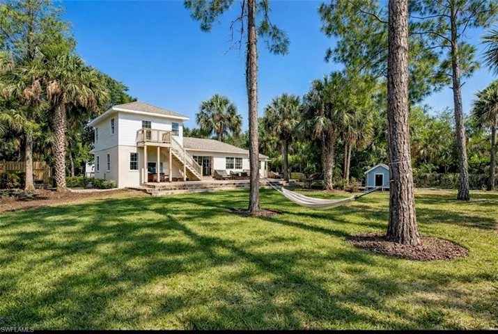 Rear view of property featuring a lawn, a shed, and a patio