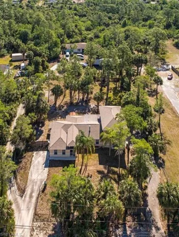 Aerial view of property and surrounding area with a heavily wooded area