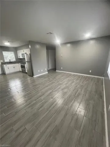 Unfurnished living room featuring hardwood / wood-style floors and sink