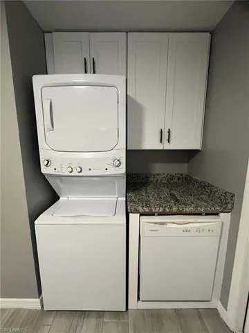 Washroom featuring stacked washing maching and dryer and light hardwood / wood-style floors