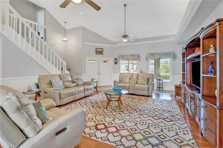 Living room with high vaulted ceiling, ceiling fan, and hardwood / wood-style floors