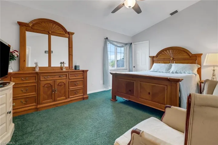 Bedroom with lofted ceiling, dark carpet, and ceiling fan