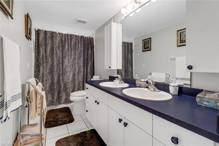 Bathroom with tile patterned flooring, double vanity, and toilet