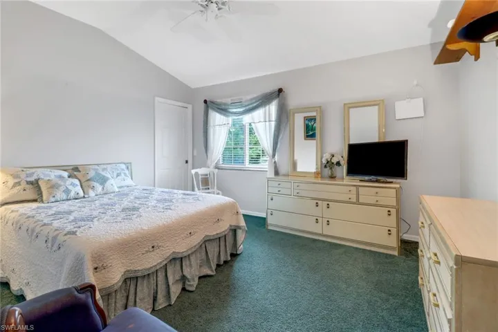 Carpeted bedroom featuring lofted ceiling and ceiling fan