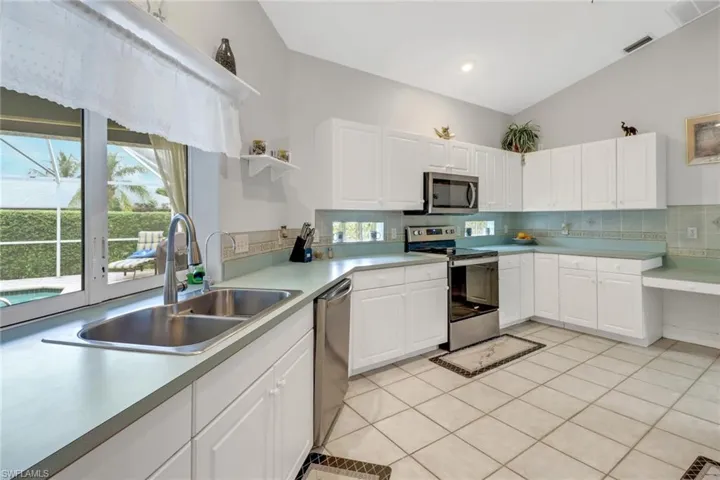Kitchen with white cabinets, stainless steel appliances, backsplash, and sink