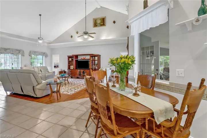 Dining room with high vaulted ceiling, ceiling fan, and light hardwood / wood-style floors