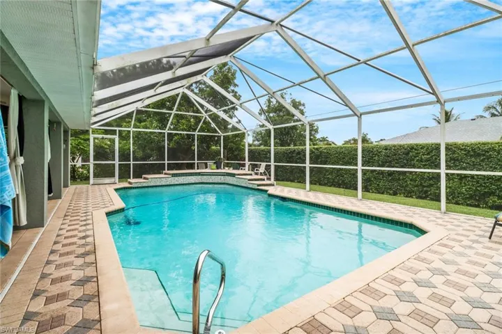 View of pool with a patio area and glass enclosure