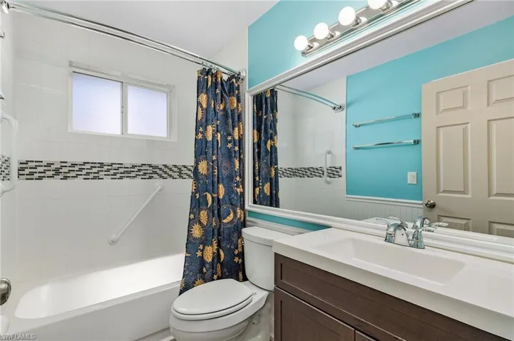 Bathroom featuring toilet, a wainscoted wall, shower / tub combo with curtain, and vanity
