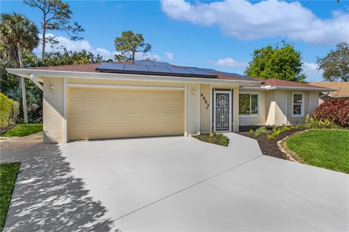 Ranch-style house with a garage, roof mounted solar panels, concrete driveway, and stucco siding