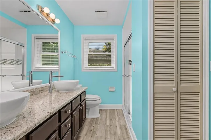 Primary Bathroom with toilet, a stall shower, a sink, and wood finished floors