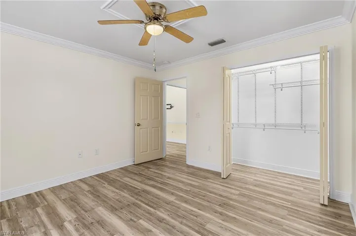 BR 1 with light wood-style floors, baseboards, visible vents, and crown molding