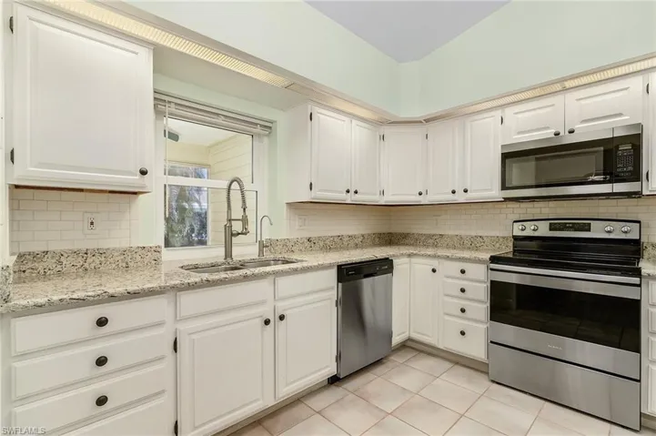 Kitchen with light tile patterned floors, a sink, white cabinetry, appliances with stainless steel finishes, and tasteful backsplash pass thru window too sunroom