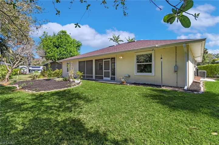 Rear view of house featuring a sunroom, stucco siding, a yard, and central AC unit