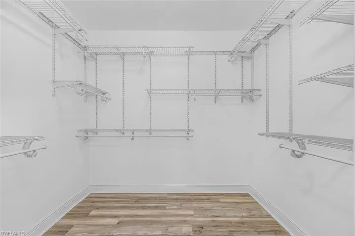 Spacious primary closet with light wood finished floors