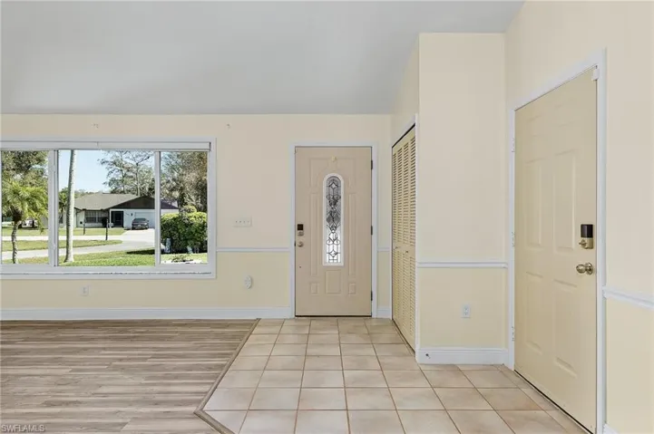 Foyer with light tile patterned floors and baseboards