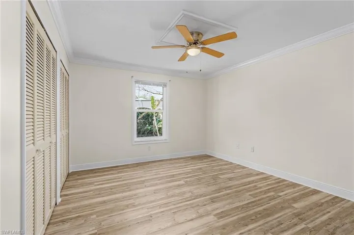 Bedroom 2 with baseboards, ornamental molding, and light wood-style floors