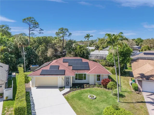View of front of house with a garage, solar panels, fence, concrete driveway, and a front yard