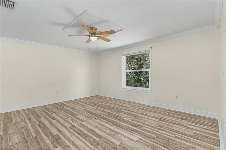 Primary BR featuring ornamental molding, light wood-type flooring, visible vents, and baseboards