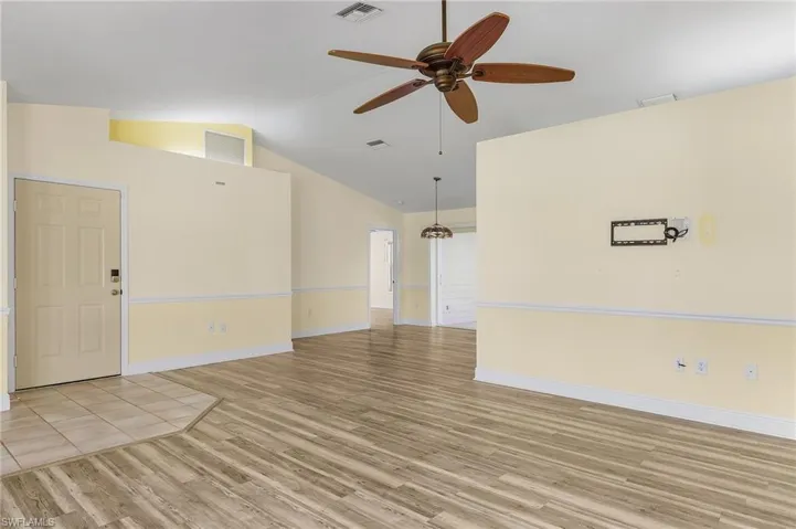 Unfurnished great room featuring vaulted ceiling, light wood-style flooring, and baseboards