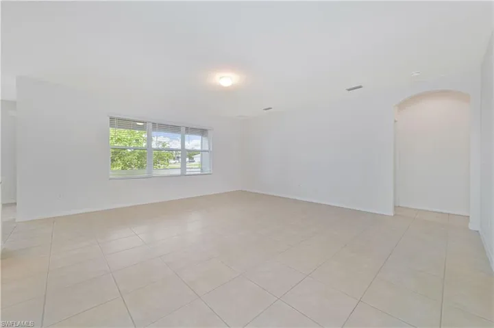 Spare room with arched walkways and light tile patterned floors