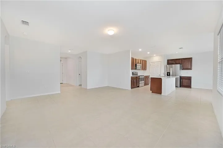 Unfurnished living room with arched walkways, recessed lighting, and light tile patterned flooring