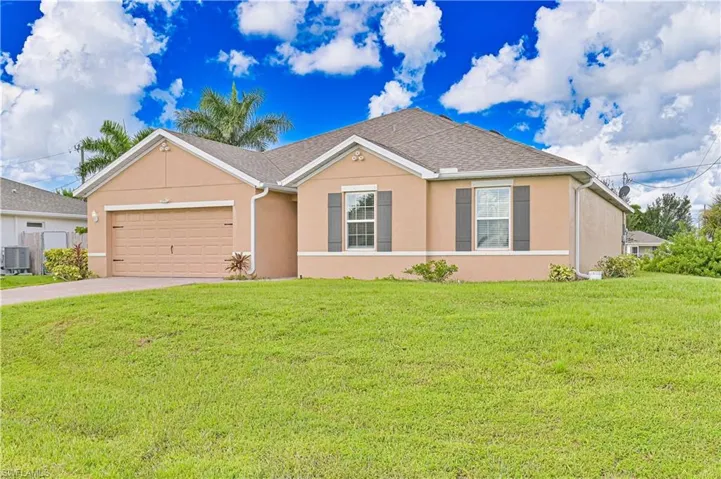 Single story home with stucco siding, an attached garage, a front yard, driveway, and a shingled roof