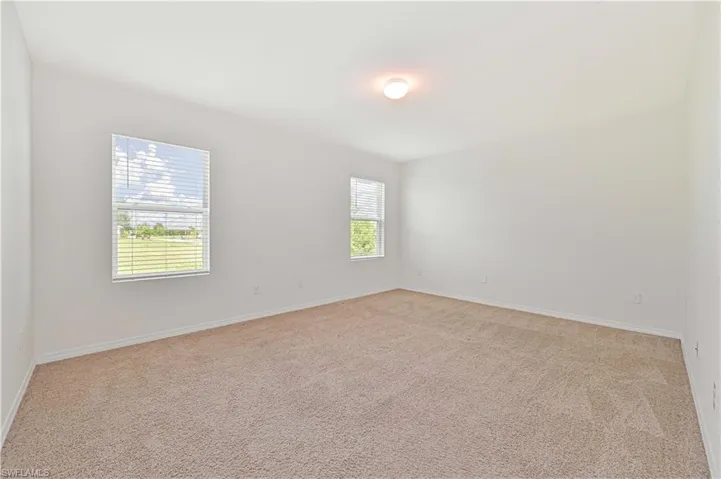 Empty room with light colored carpet and baseboards