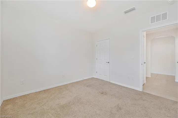 Empty room featuring arched walkways and light carpet