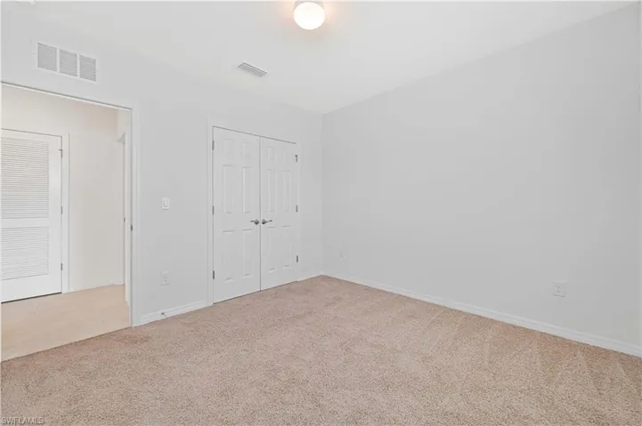 Unfurnished bedroom with light colored carpet, a closet, and light tile patterned floors