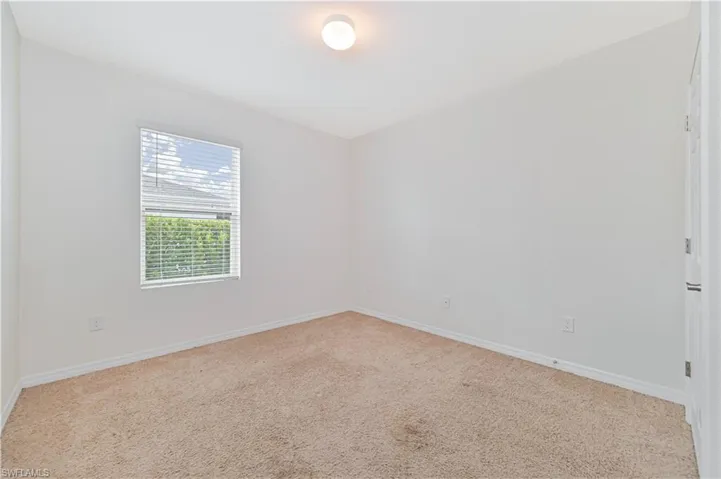 Carpeted spare room featuring baseboards