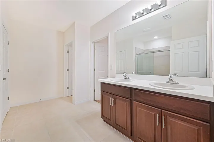 Bathroom featuring a stall shower, double vanity, and light tile patterned floors