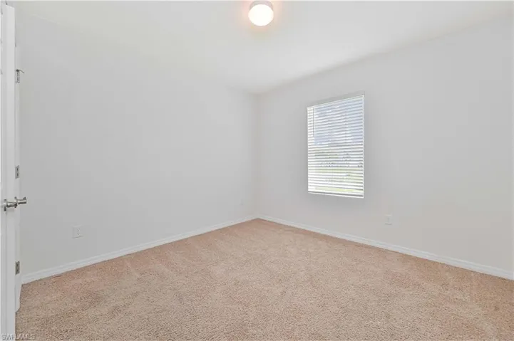 Unfurnished room with light colored carpet and baseboards