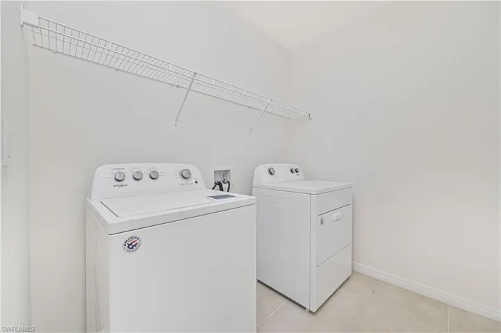 Laundry area with light tile patterned flooring and washer and clothes dryer