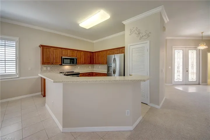 Kitchen featuring healthy amount of natural light, decorative backsplash, stainless steel appliances, french doors, and crown molding