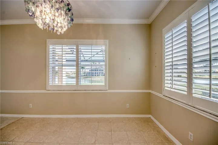Empty room featuring crown molding, a chandelier, and light tile patterned floors