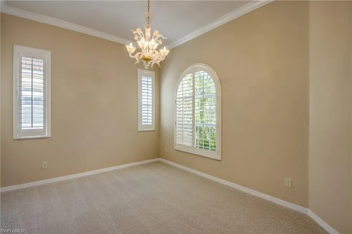 Carpeted empty room with suspended lighting and ornamental molding