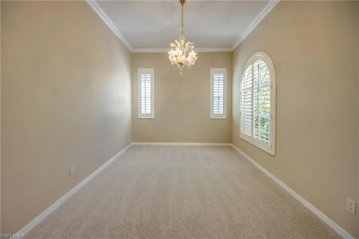 Unfurnished room with light colored carpet, ornamental molding, and a chandelier