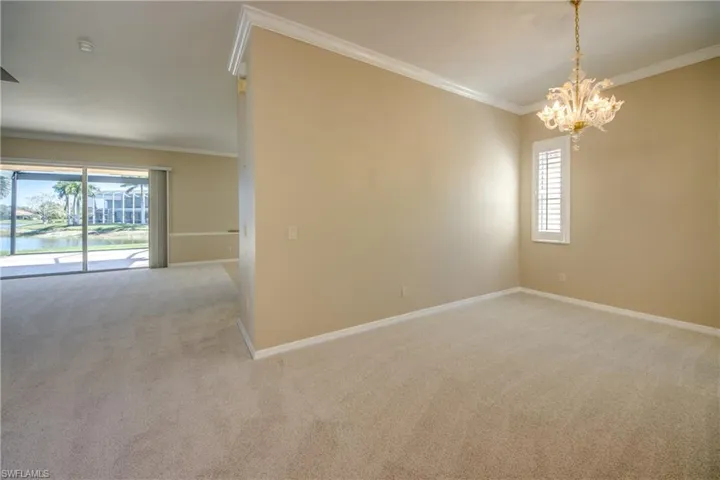 Empty room featuring ornamental molding, light carpet, a chandelier, and a water view