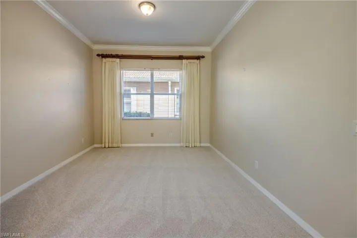 Spare room with crown molding and light colored carpet