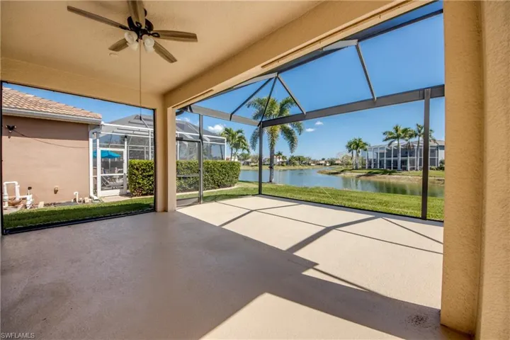 View of patio featuring ceiling fan, glass enclosure, a sunroom, and a water view