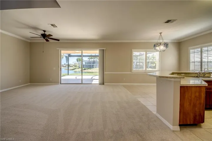 Kitchen featuring open floor plan, light tile patterned flooring, light carpet, hanging lights, and a water view