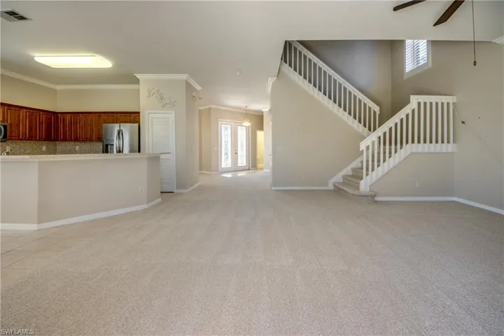 Unfurnished living room with a ceiling fan, light carpet, french doors, and ornamental molding