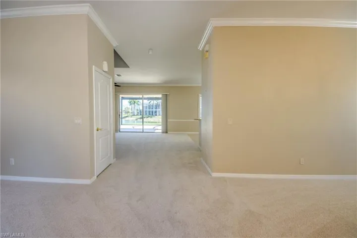 Hallway with ornamental molding and light carpet