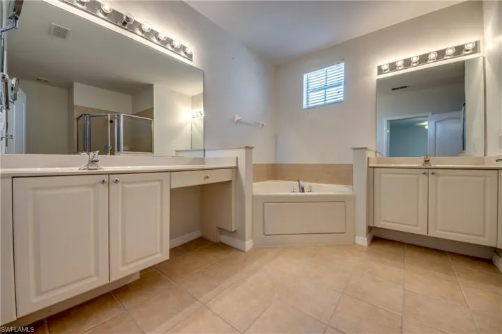 Bathroom with two vanities, a shower stall, a bath, and light tile patterned flooring