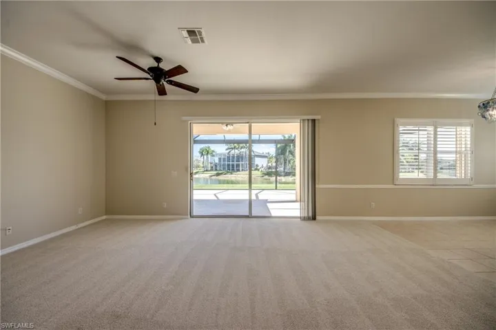 Empty room featuring crown molding, ceiling fan, and light colored carpet